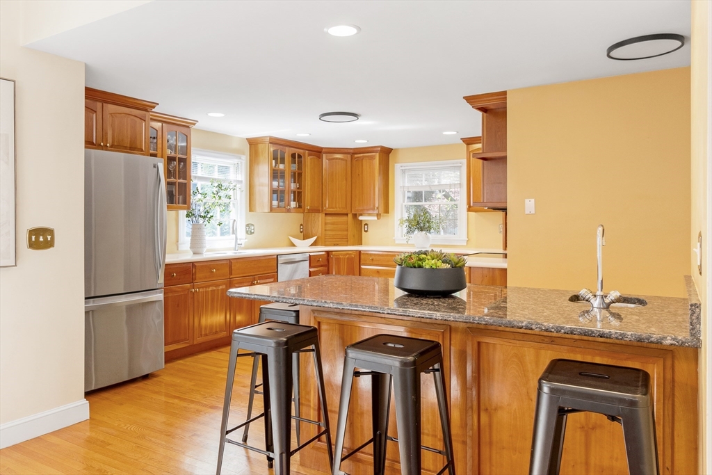 55 Berkshire Road Needham, MA 02492 - Photo 8 of 33 a kitchen with stainless steel appliances granite countertop a stove a refrigerator a sink a dining table and chairs with wooden floor