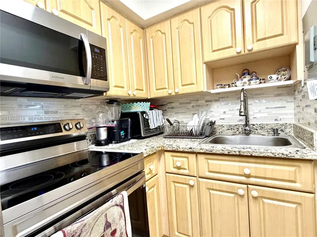 a kitchen with stainless steel appliances granite countertop a stove a sink and a microwave