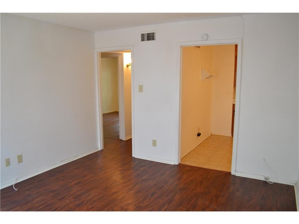 a view of an empty room with wooden floor and closet