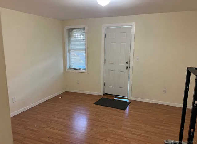 an empty room with wooden floor and window