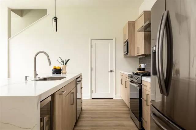 a kitchen with stainless steel appliances granite countertop a refrigerator a stove and a sink with wooden floor