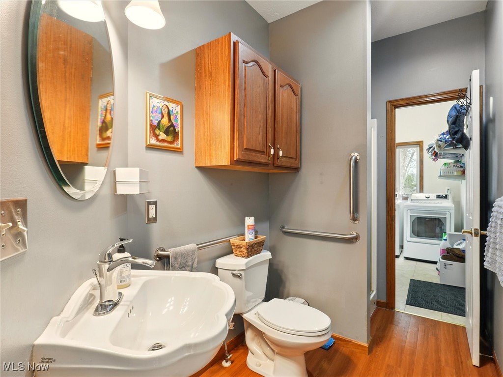 2068 Chimney Ridge Drive Madison, OH 44057 - Photo 14 of 37 main floor full bathroom featuring a sink, toilet, washer / dryer, and wood finished floors