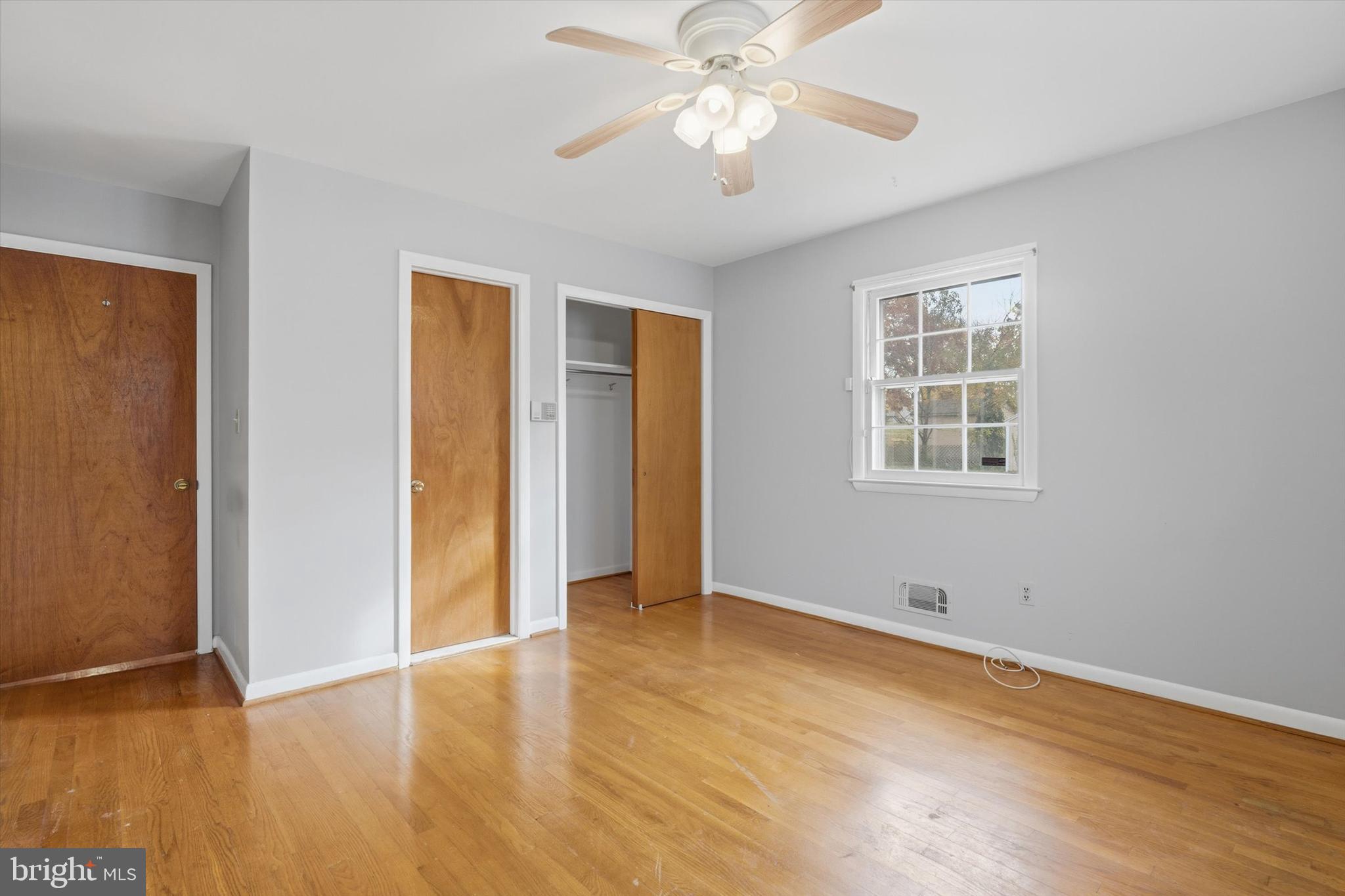 697 West Maple Road Linthicum Heights, MD 21090 - Photo 18 of 36 an empty room with wooden floor chandelier fan and windows