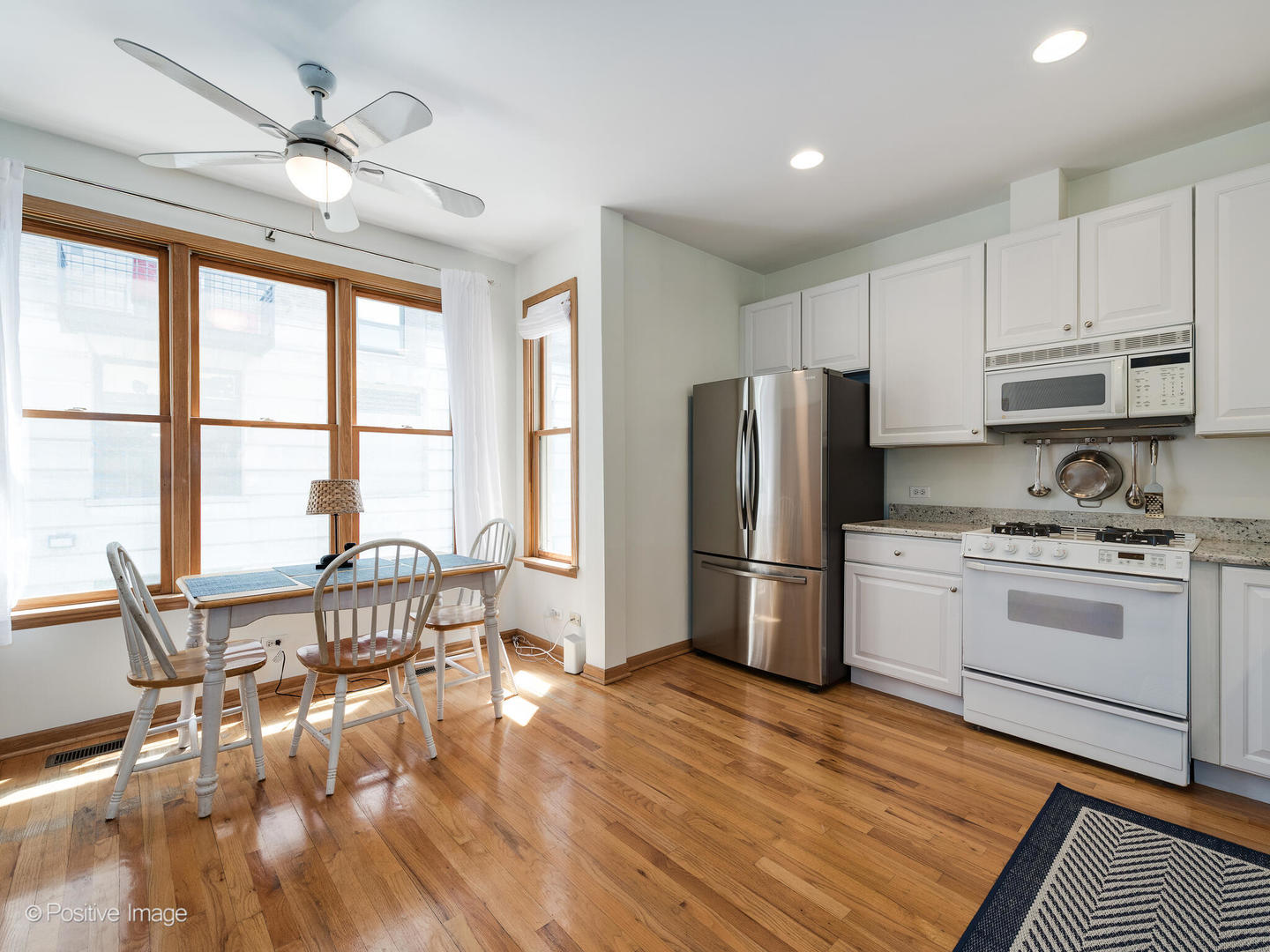 1215 West Lexington Street, Unit E Chicago, IL 60607 - Photo 7 of 21 a kitchen with a refrigerator a stove a dining table and chairs with wooden floor