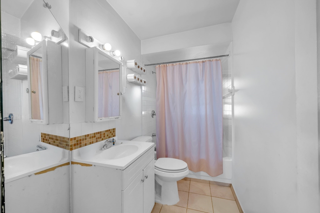 103 Ash Street Nashua, NH 03060 - Photo 10 of 36 a bathroom with a sink a toilet a mirror and shower curtain