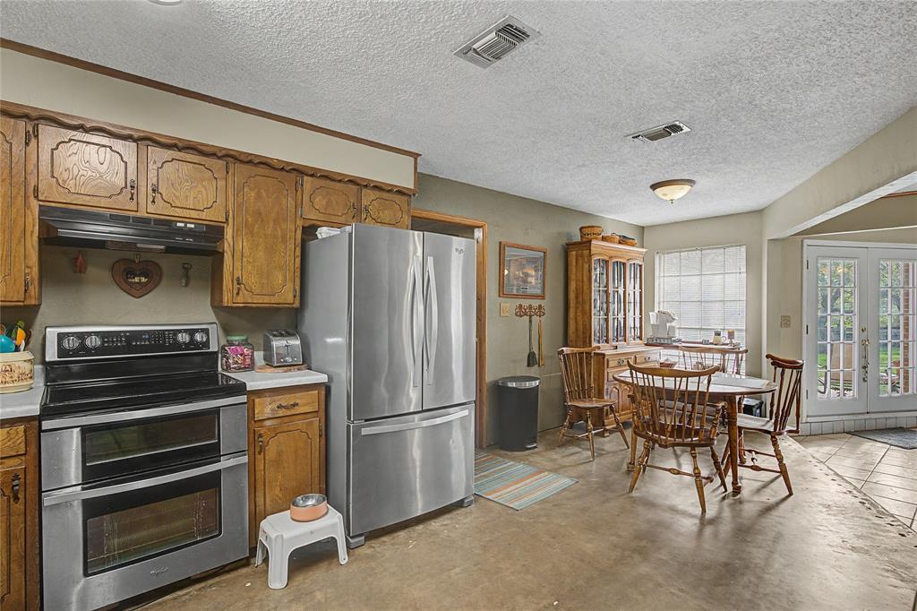 243 County Road 3851 Poolville, TX 76487 - Photo 13 of 34 a kitchen with stainless steel appliances granite countertop a refrigerator and a stove top oven