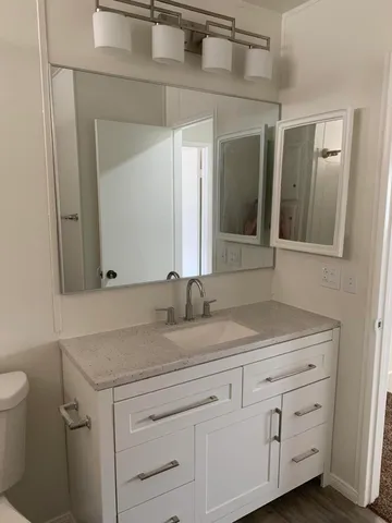 a bathroom with a granite countertop sink mirror and toilet