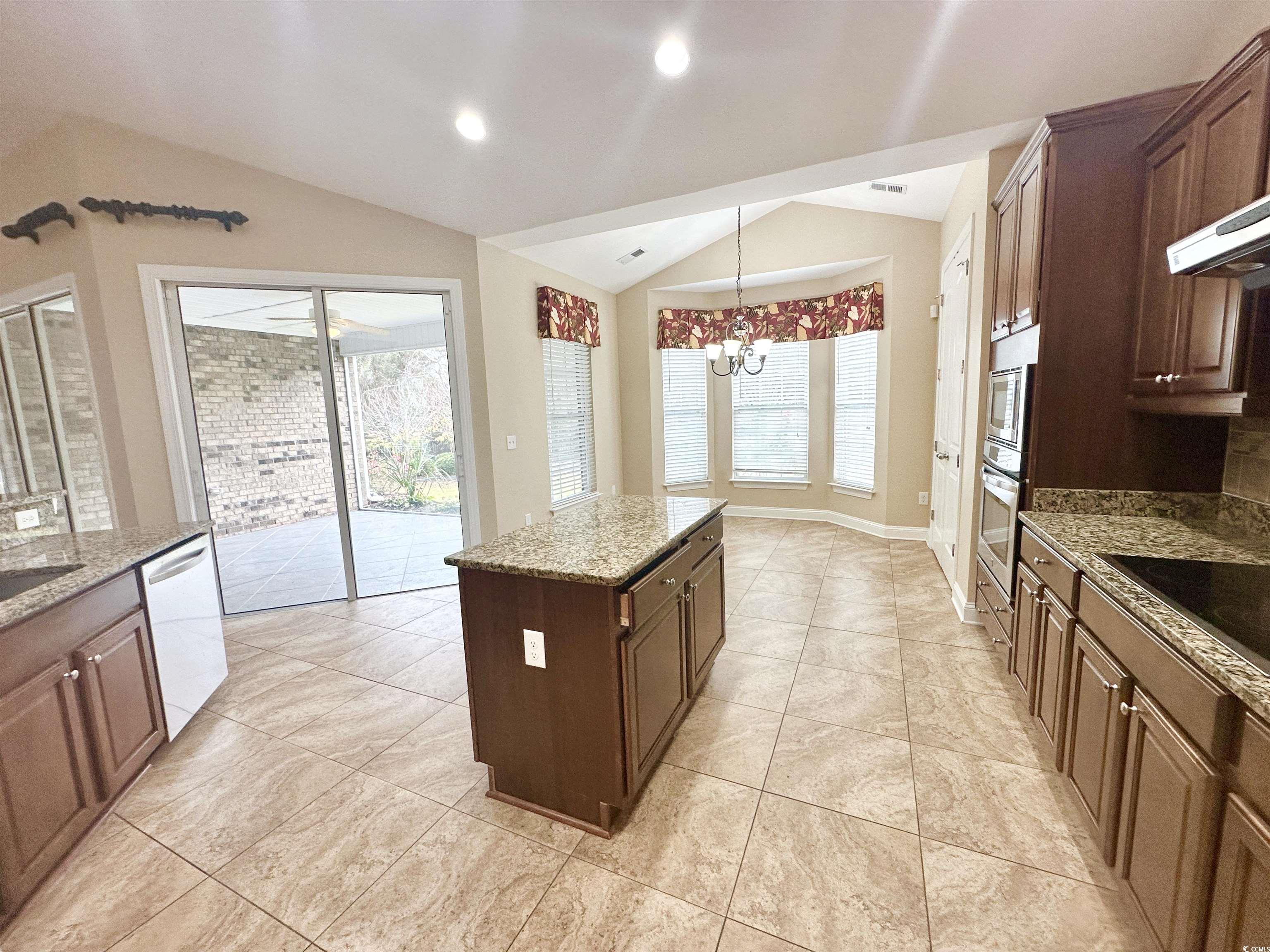 8472 Juxa Drive Myrtle Beach, SC 29579 - Photo 10 of 35 Kitchen with lofted ceiling, light stone countertops, hanging light fixtures, a kitchen island, and a chandelier