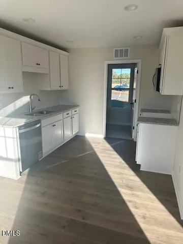 a kitchen with granite countertop a stove a sink and a refrigerator