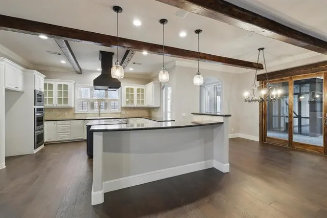 a large kitchen with a large counter top a sink stainless steel appliances and cabinets