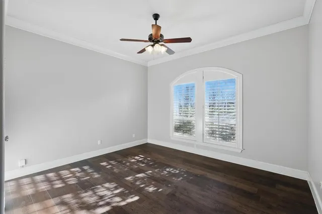 an empty room with wooden floor ceiling fan and window