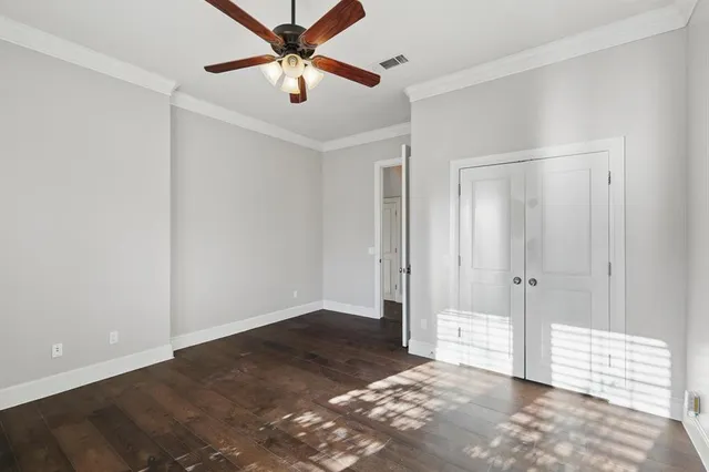 an empty room with closet and a ceiling fan