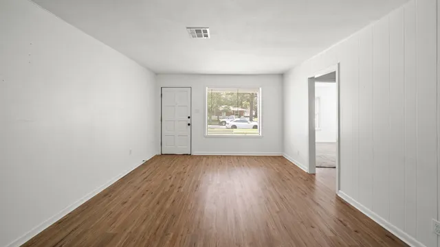 an empty room with wooden floor and windows