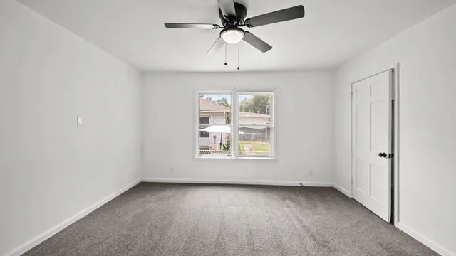 an empty room with a window and a fan
