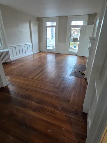 a view of an empty room with wooden floor and windows