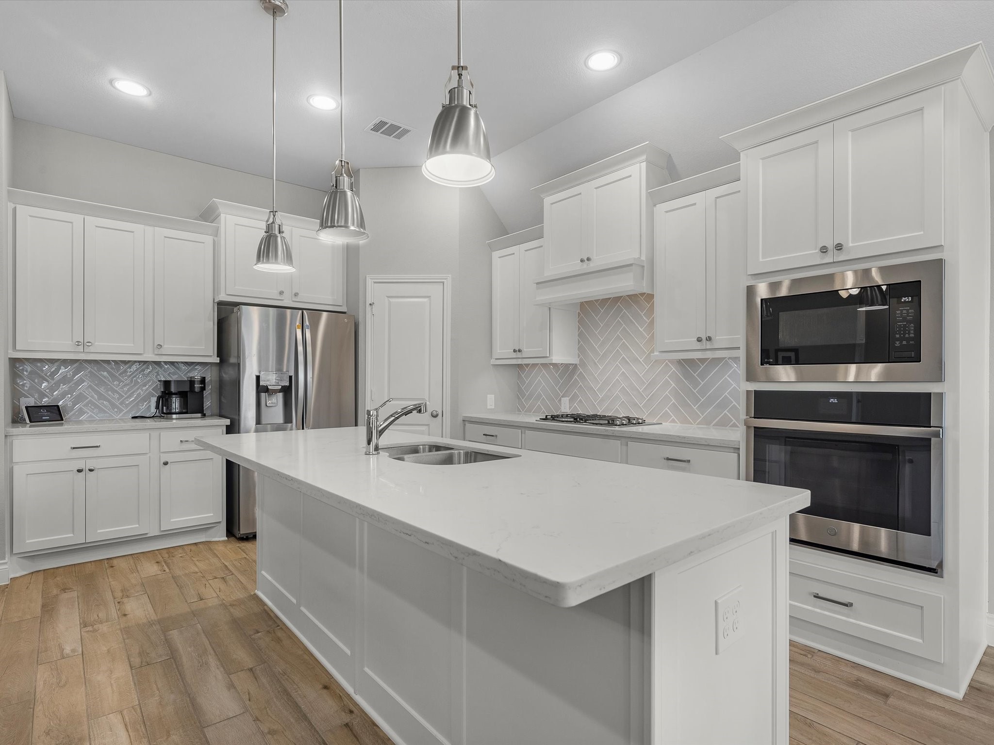 10135 Napier Drive Rosharon, TX 77583 - Photo 7 of 36 Stainless steel appliances, chrome finishes, and a separate cooktop with vent hood create a modern, functional design.