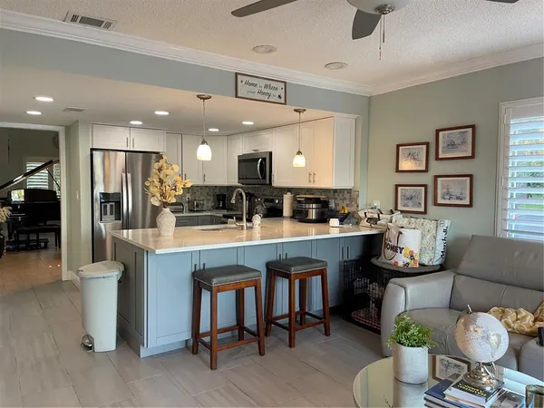 a kitchen with stainless steel appliances kitchen island granite countertop a refrigerator a stove a sink dishwasher with a dining table and chairs with wooden floor