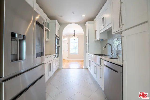 a large kitchen with stainless steel appliances a sink and cabinets