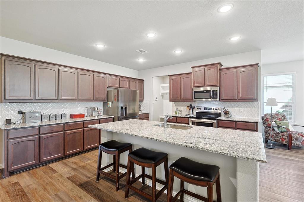 808 Feather Edge Drive Springtown, TX 76082 - Photo 1 of 40 a kitchen with stainless steel appliances granite countertop a table chairs sink refrigerator and cabinets