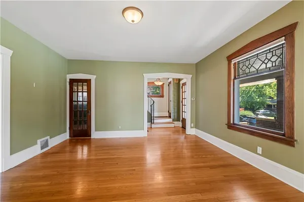 a view of an empty room with window and wooden floor
