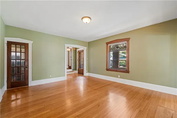 a view of an empty room with window and wooden floor