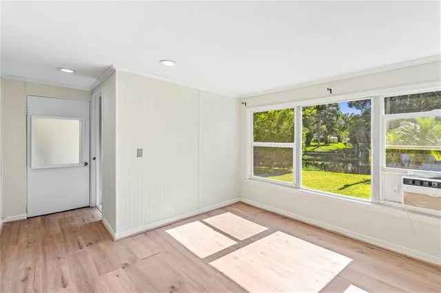 a view of an empty room with wooden floor and a window