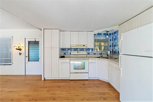 a kitchen with stainless steel appliances granite countertop a refrigerator sink and white cabinets