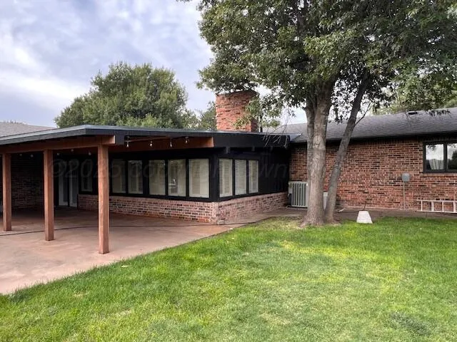 a view of a house with a yard and a large tree