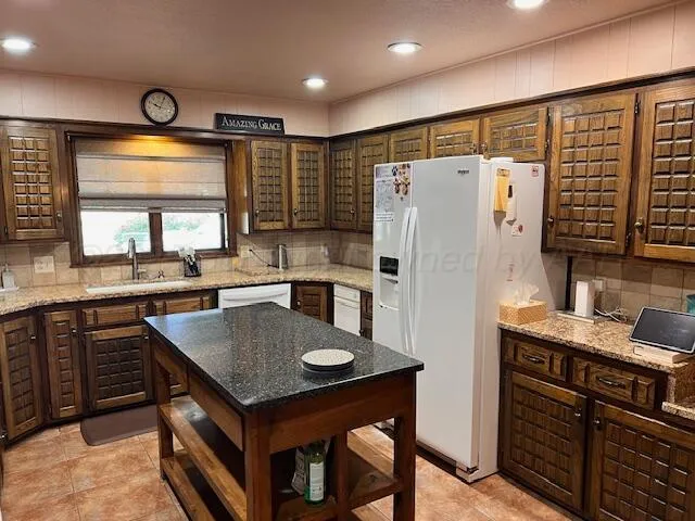 a kitchen with granite countertop a table chairs sink and refrigerator