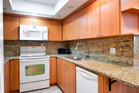 a kitchen with granite countertop a sink stove and cabinets