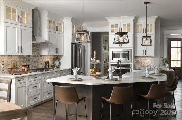 a kitchen with stainless steel appliances kitchen island granite countertop a dining table chairs and a refrigerator