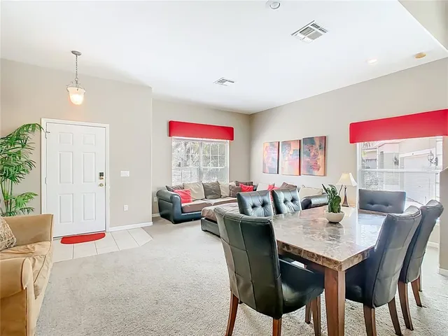 a kitchen with stainless steel appliances granite countertop a refrigerator a stove a sink a dining table and chairs with white cabinets