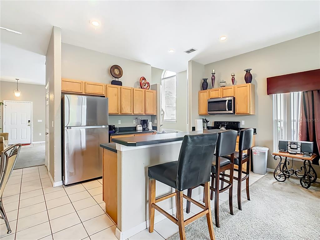 334 Cadiz Loop Davenport, FL 33837 - Photo 19 of 63 a kitchen with stainless steel appliances granite countertop a refrigerator a stove a sink a dining table and chairs with white cabinets