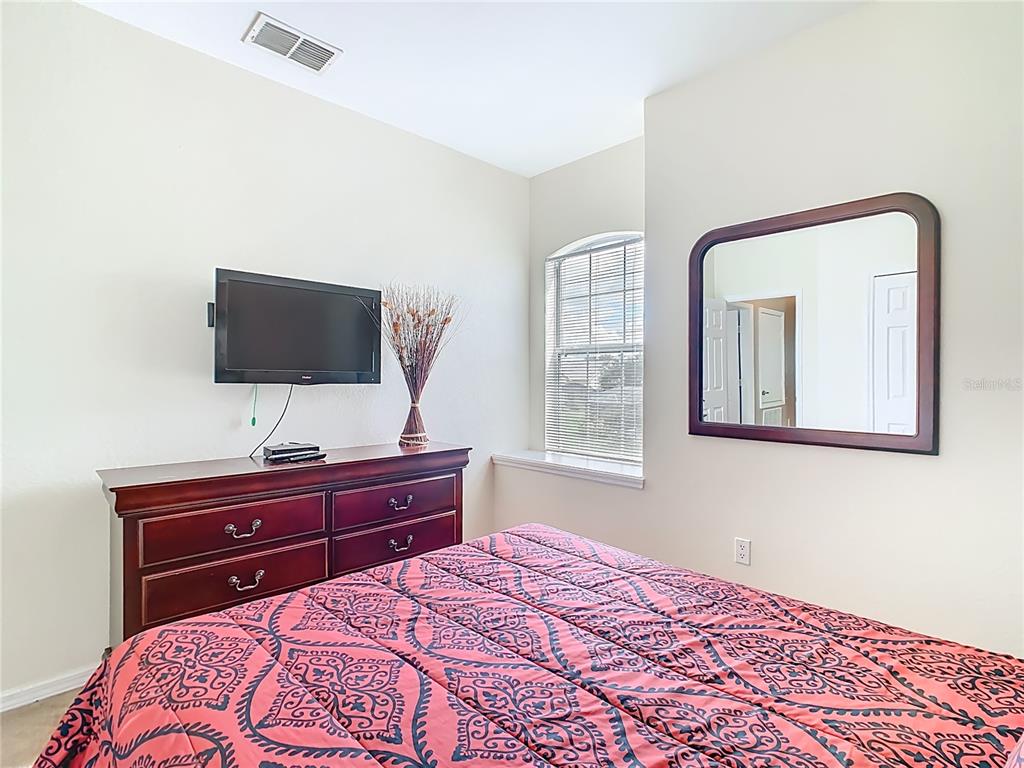 334 Cadiz Loop Davenport, FL 33837 - Photo 34 of 63 a bedroom with a bed and a flat screen tv