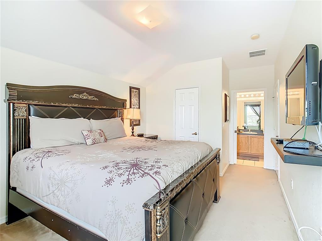 334 Cadiz Loop Davenport, FL 33837 - Photo 45 of 63 a spacious bedroom with a bed and a flat screen tv