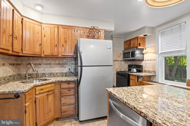 a kitchen with stainless steel appliances granite countertop a refrigerator stove and sink