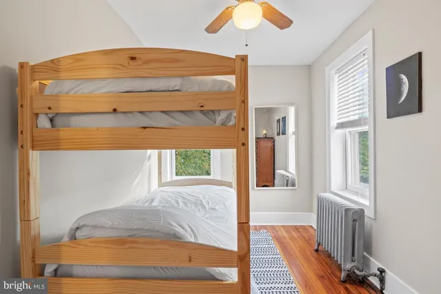 a view of a bedroom with wooden floor and ceiling fan