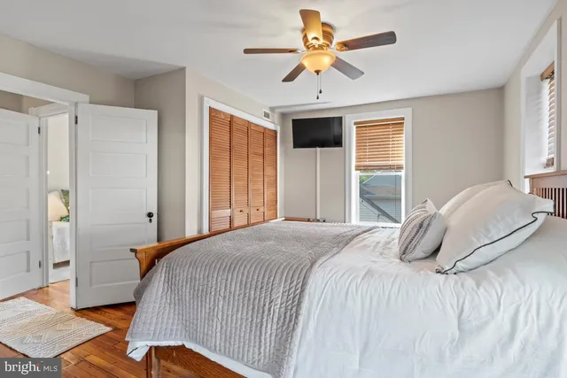 a bedroom with a large bed ceiling fan and a window