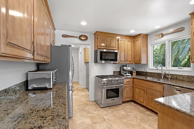a kitchen with stainless steel appliances granite countertop a sink a stove a refrigerator cabinets and a dining table