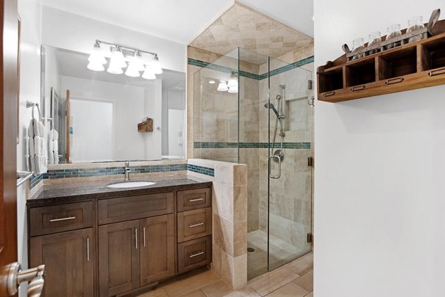 a bathroom with a granite countertop sink a mirror and shower
