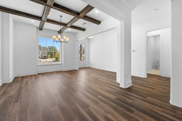 an empty room with wooden floor a ceiling fan and windows