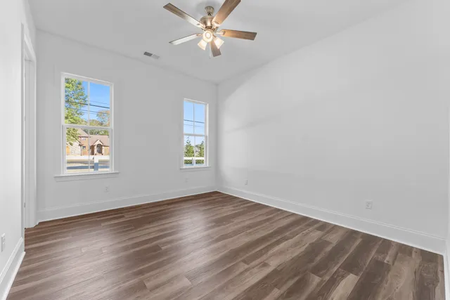 a view of empty room with wooden floor and fan
