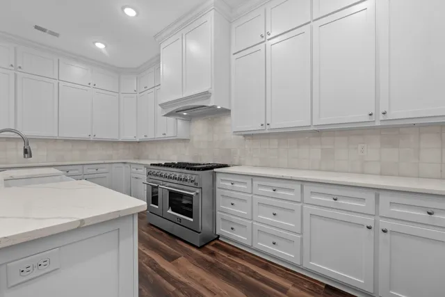 a kitchen with granite countertop white cabinets and stainless steel appliances