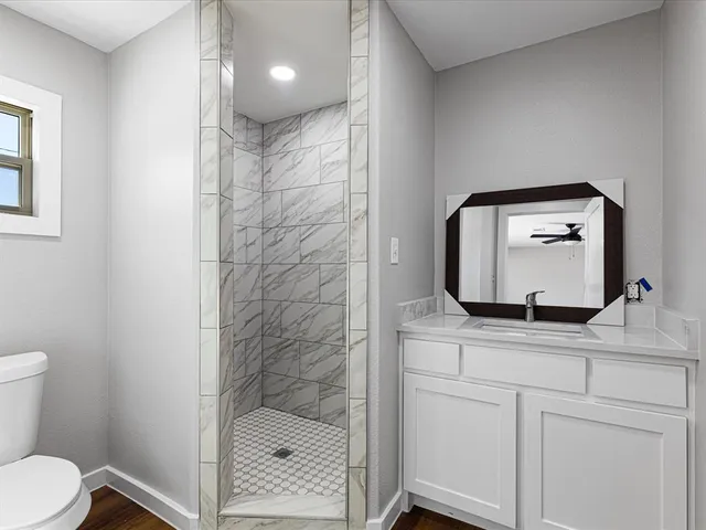 a bathroom with a granite countertop sink toilet and mirror