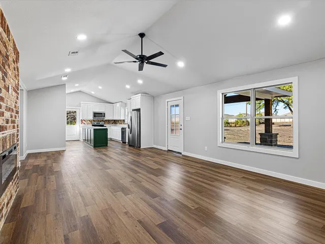 a view of an empty room with window and wooden floor