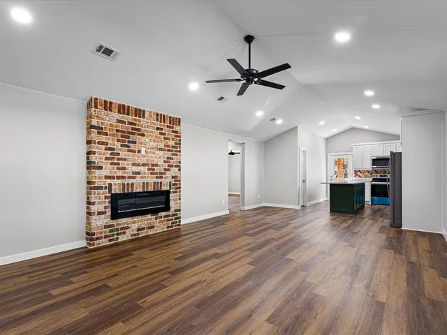 a view of an empty room with wooden floor a ceiling fan and windows