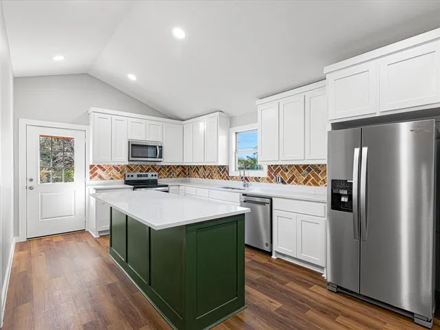 a kitchen with kitchen island a sink a stove a refrigerator cabinets and a center island