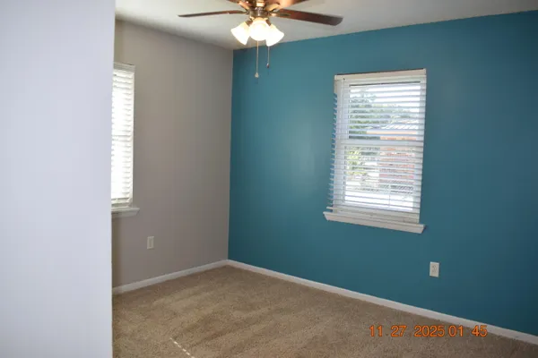 an empty room with a window and a chandelier fan