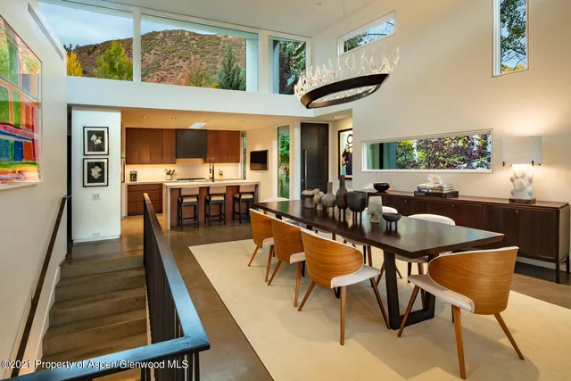 a dining room with furniture a floor to ceiling window and kitchen view