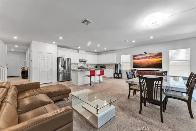 a living room with kitchen island furniture and a dining table with kitchen view